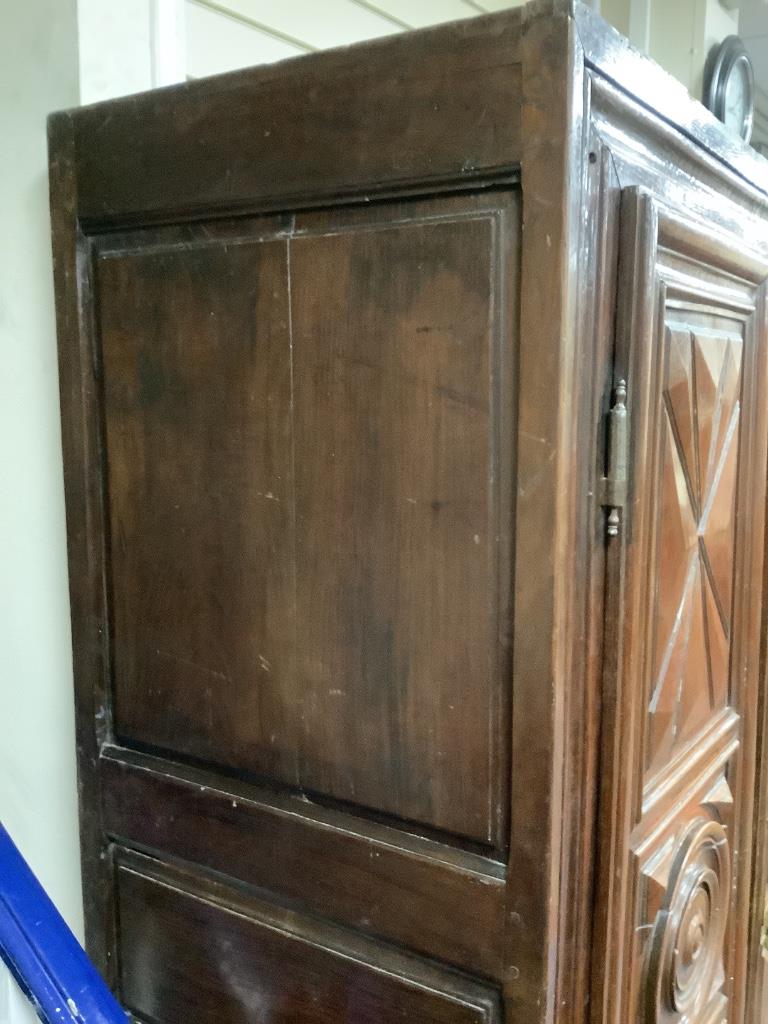 A large fruitwood double wardrobe / armoire, with twin carved panelled doors below a dentil frieze, raised on squat bun feet, 18th century, width 130cm, depth 62cm, height 198cm